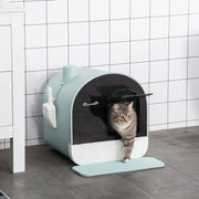 Enclosed cat litter box with lid and scoop, splash-proof design, easy to clean, with a cat stepping out on a tiled floor.